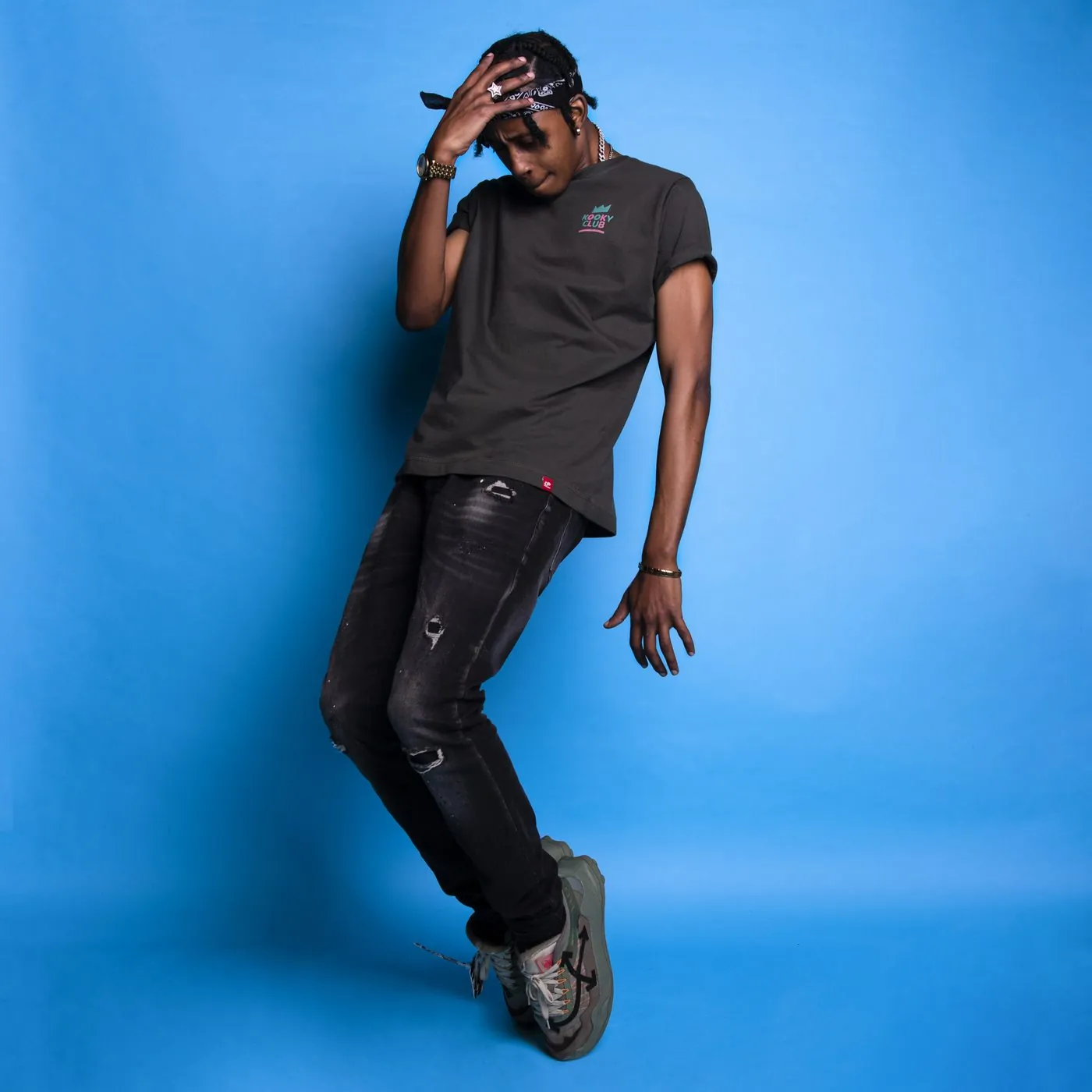 Model in a Kooky Club T-shirt striking a dance pose against a bright blue backdrop
