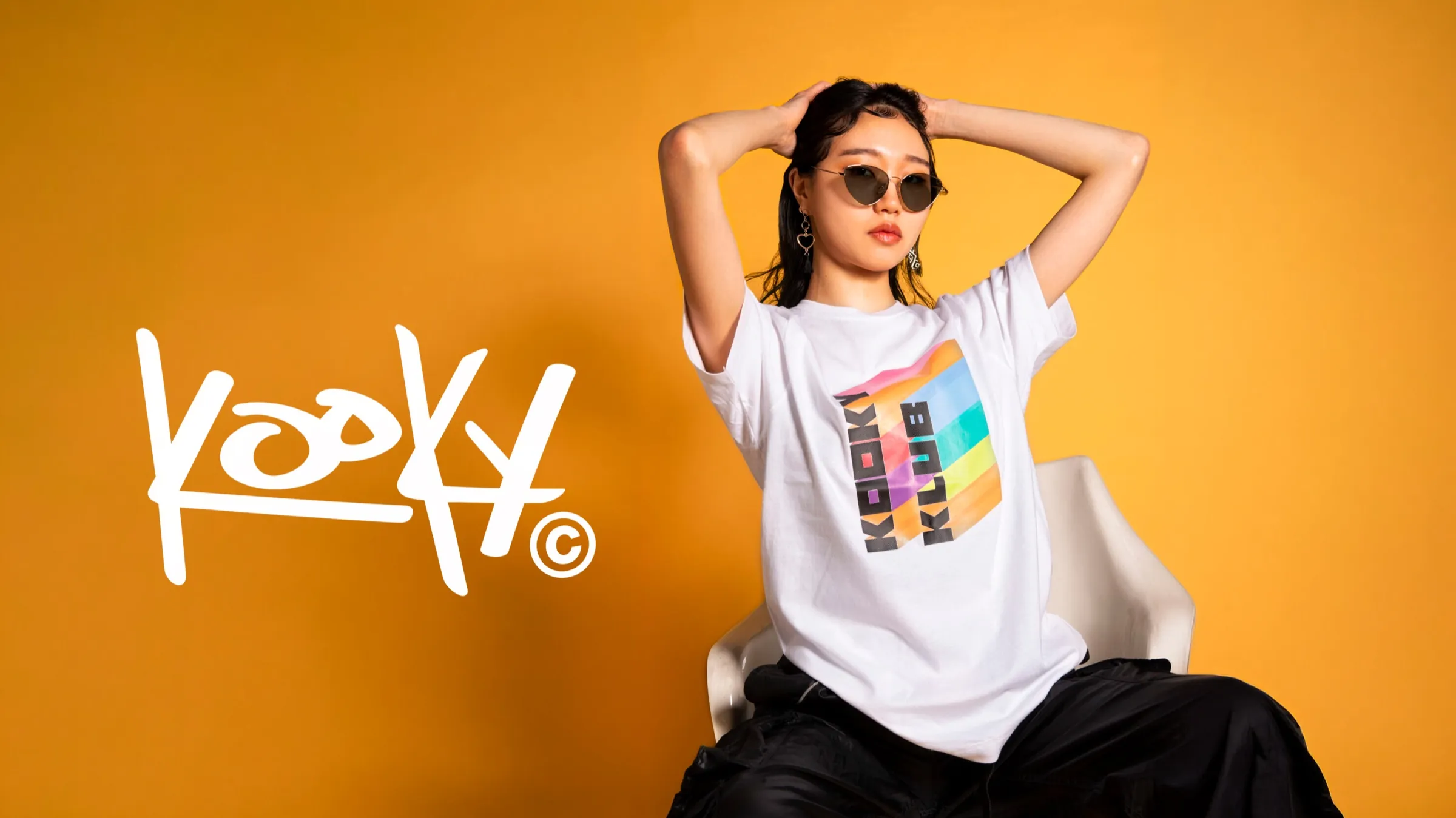 Kooky Club apparel campaign featuring a model in a branded T-shirt against a bright orange background